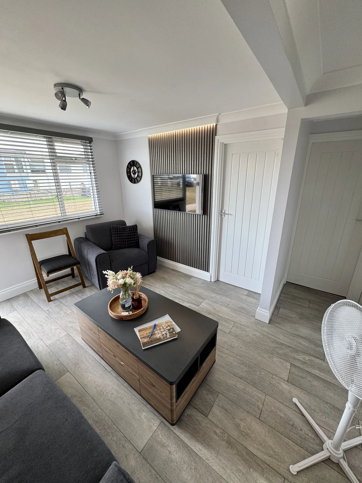Yaverland Breeze living room with the TV mounted on a wooden slatted feature wall, beside the sofa and armchair